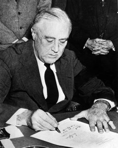President Roosevelt, wearing a black armband, signs the declaration of war against Japan on December 8, 1941